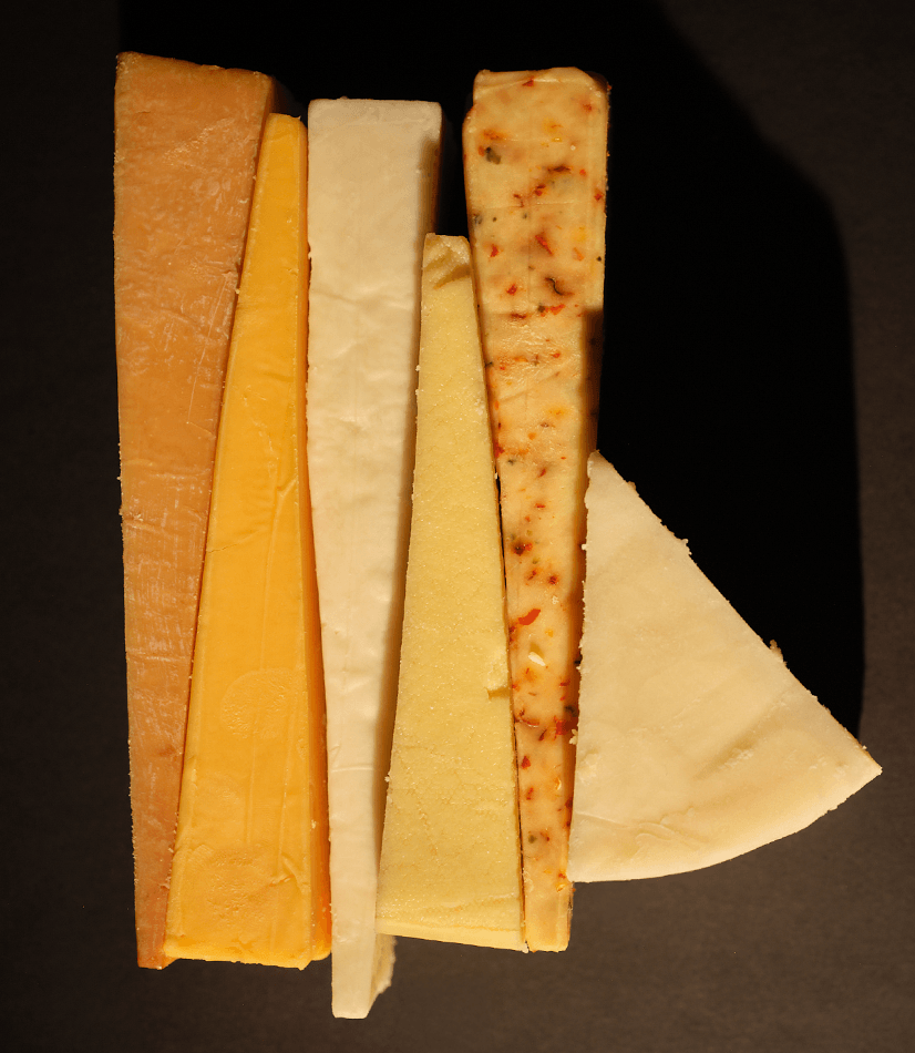 Greens of Glastonbury Cheese presented in thin triangles on a black background.