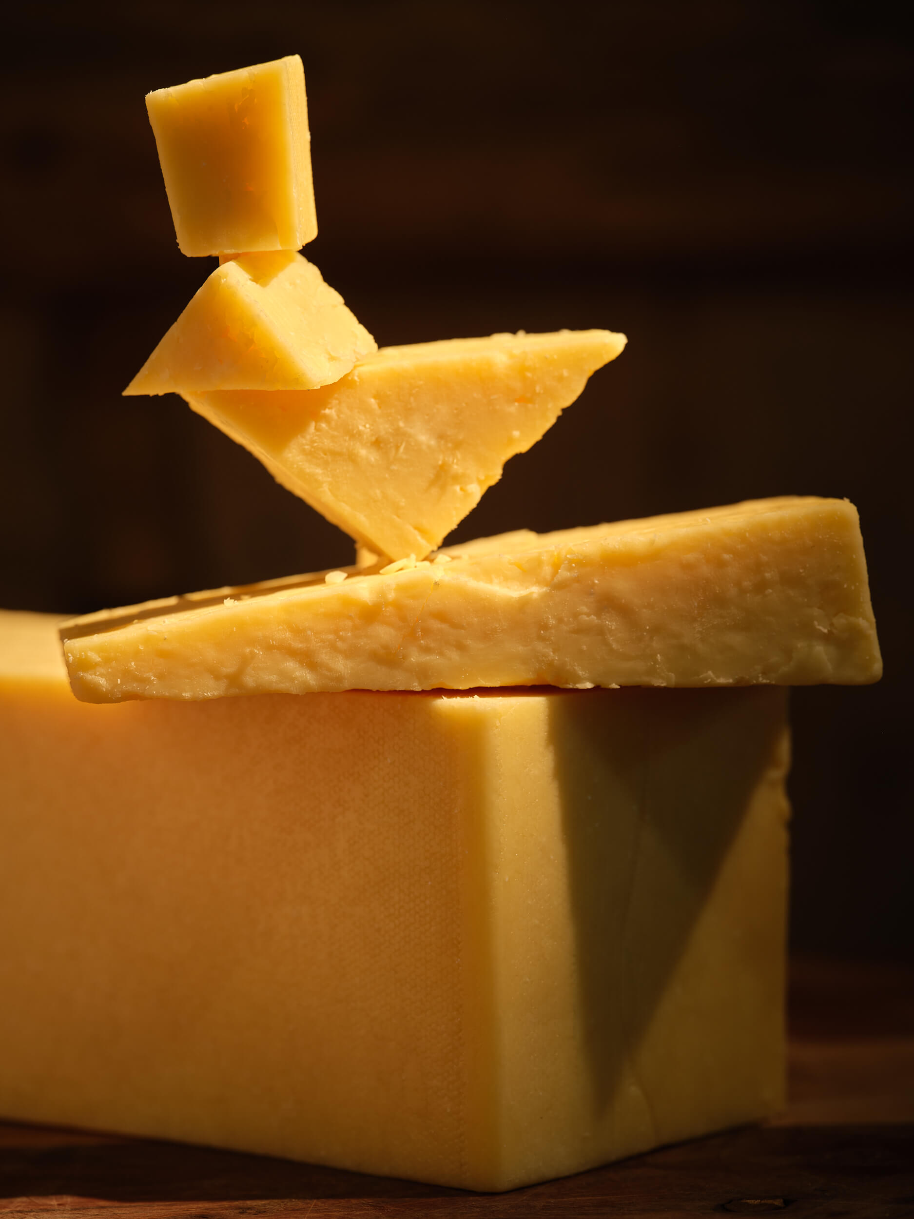 Greens of Glastonbury Twanger Cheese stacked creatively on a black background.