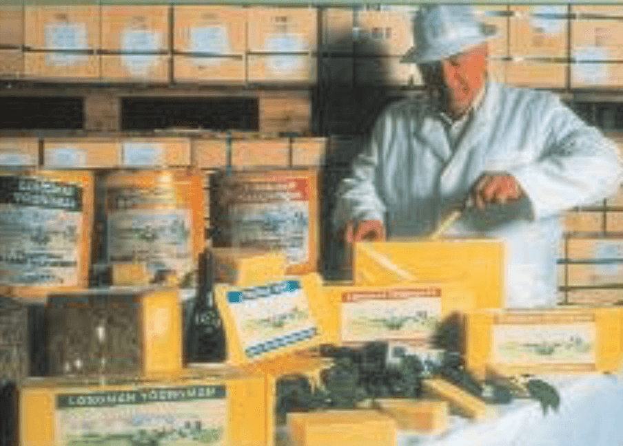 Historic photo of Richard Longman cutting a variety of cheeses in different sizes.