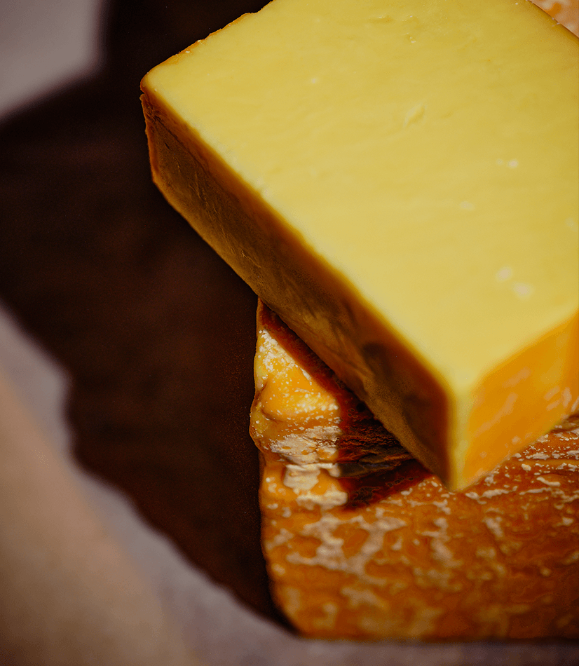Smokacre mildly smoked cheddar cheese from Longmans. Two pieces positioned on top of each other.